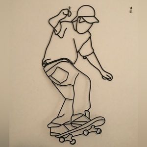Black metal wall art of outline of skateboarder.